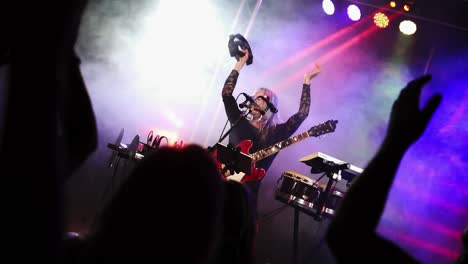 Blonde-mature-woman-on-stage-playing-the-tambourine-for-the-lively-audience