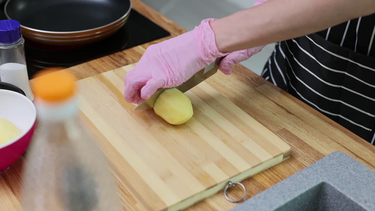 Cutting peeled potatoes on a wooden cutting board in the kitchen