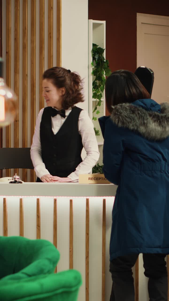 Video verticale Turista asiatica che parla con l'addetto alla reception