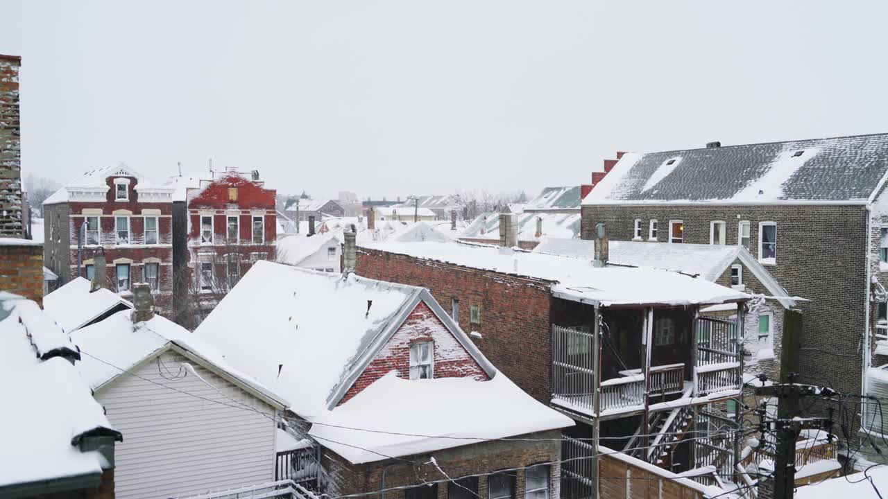 vista estática de casas de ladrillo cubiertas de una capa de nieve durante la ráfaga de nieve ligera en el frío día de invierno