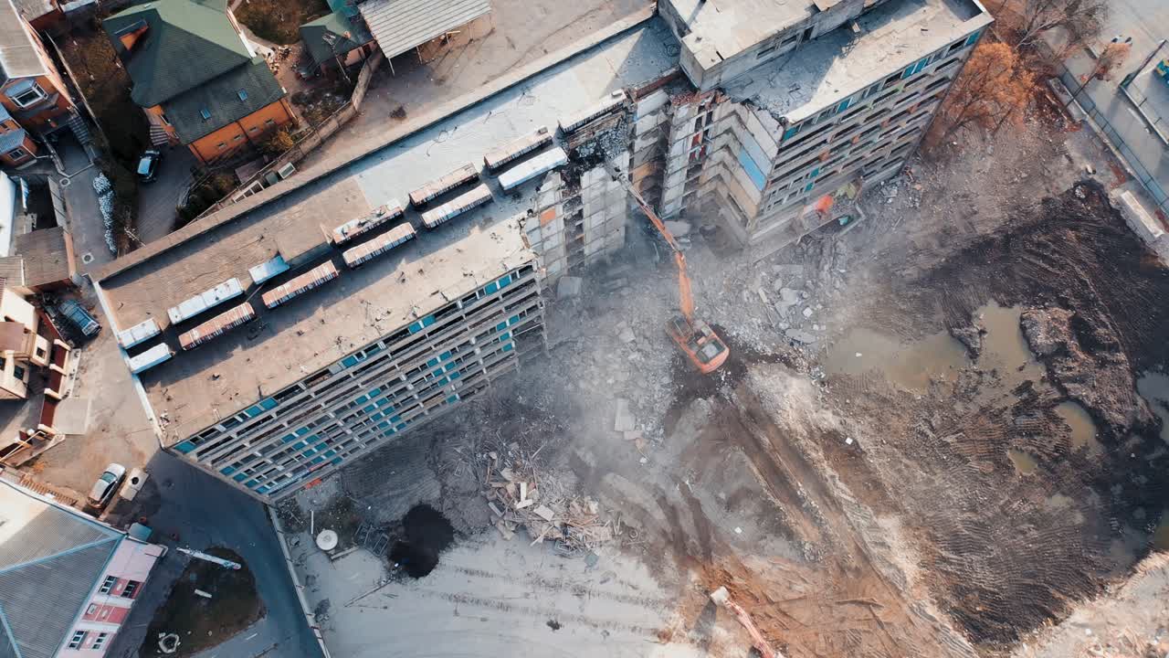 Aerial View Excavators Dismantle The Concrete Structures Of The Building. Powerful claw of excavator demolishing the ruined building
