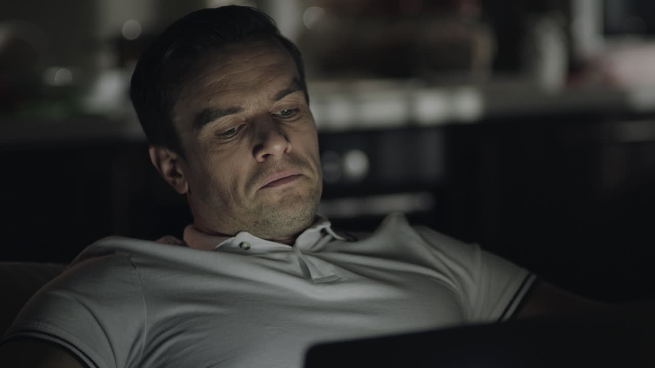 클로즈업 피곤한 남자가 집 사무실에서 노트북으로 늦게 일하고 있습니다.