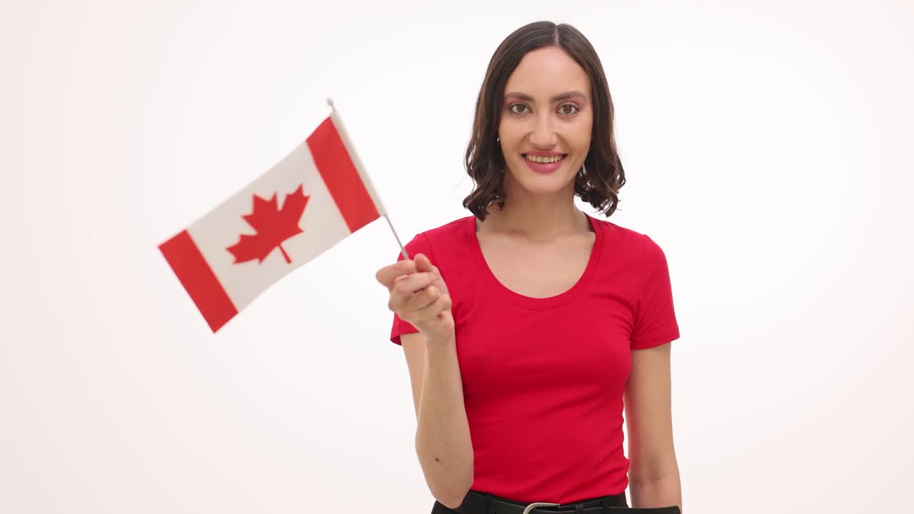 Joven mujer agitando una pequeña bandera canadiense y sonriendo