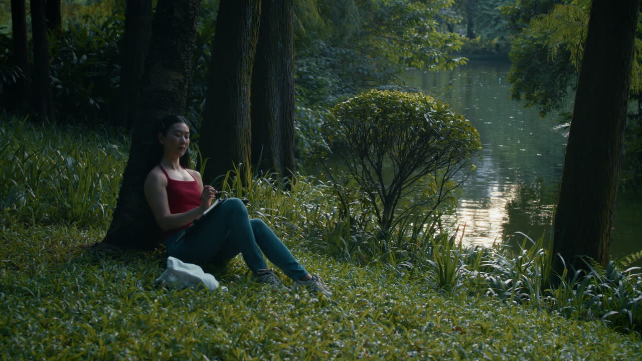 Donna che scrive in un parco in riva a un lago