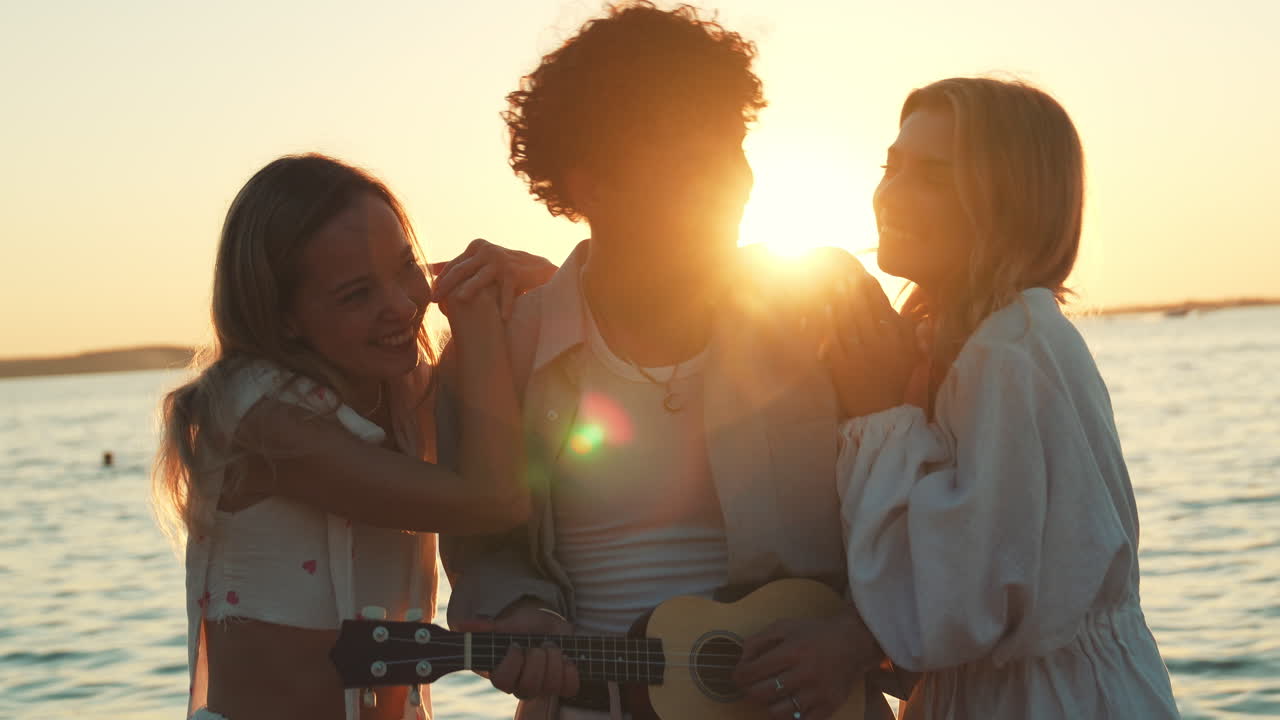 Amici che si godono una sessione di ukulele al tramonto in spiaggia