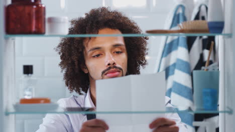 vista a través del gabinete del baño de un joven empresario practicando el discurso antes de ir a trabajar
