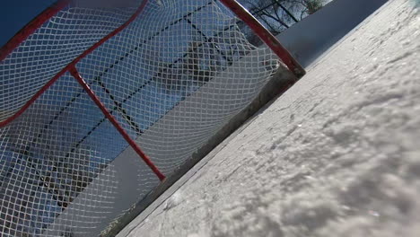 ice hockey puck being shot into the net on an outdoor rink