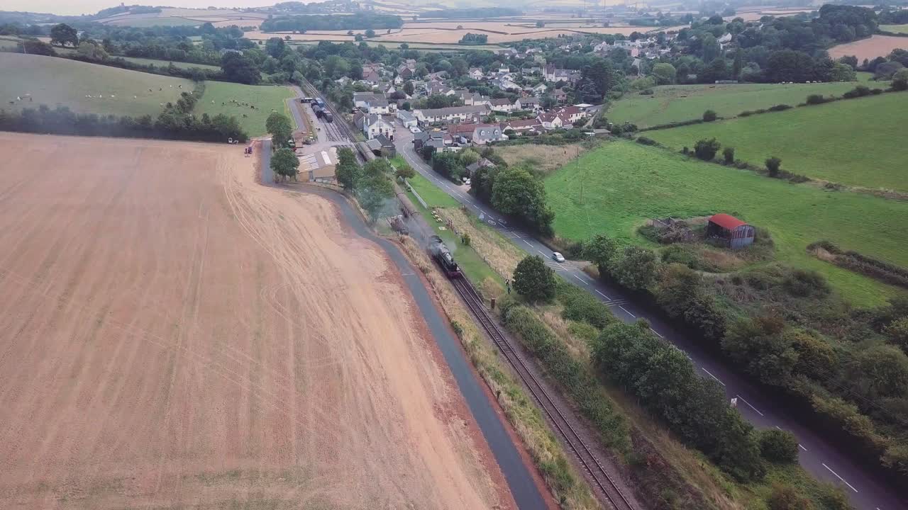 영국 시골에 있는 작은 역으로 들어선 증기 엔진 고정 장치 위로 공중 폭 추적