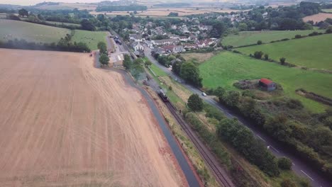 Aerial-wide-tracking-forward-over-a-Steam-engine-stationary-that-has-pulled-into-a-small-station-in-the-English-Countryside