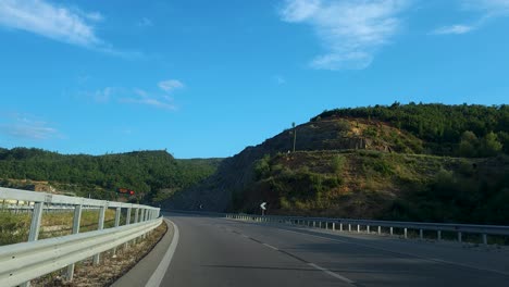 driving through tunnel in panoramic beautiful road in albania, mountain with green forests and blue sky to dark tunnel with lights