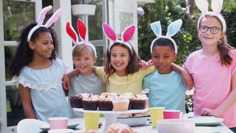 portrait of children wearing bunny ears enjoying outdoor easter party in garden at home