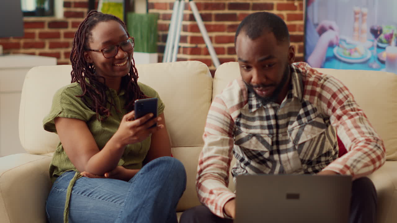 Man and woman browsing smartphone and laptop at home