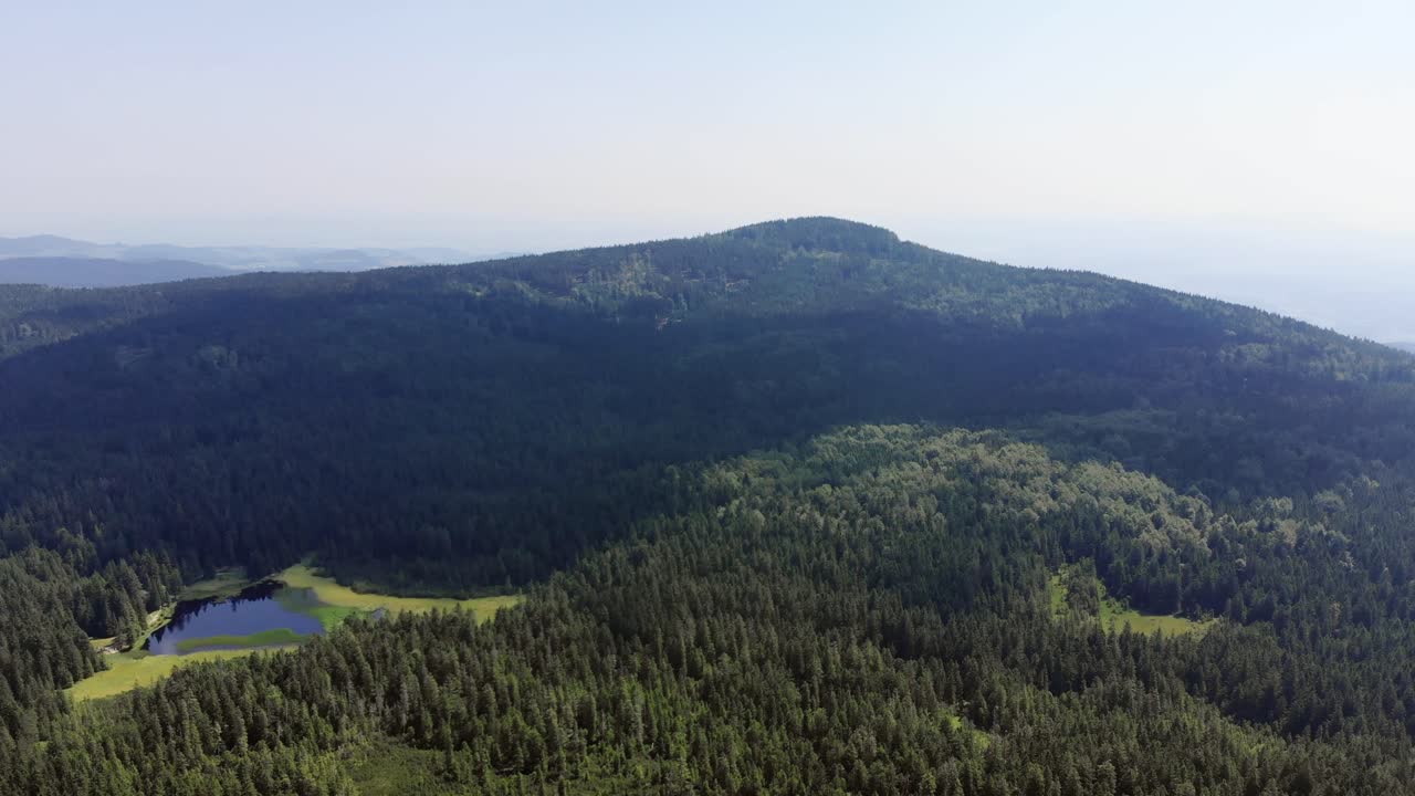 High aerial drone view approaching Black Lake and green mountain, Oplotnica, Slovenia