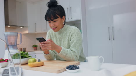 woman using phone in the kitchen while preparing a healthy meal