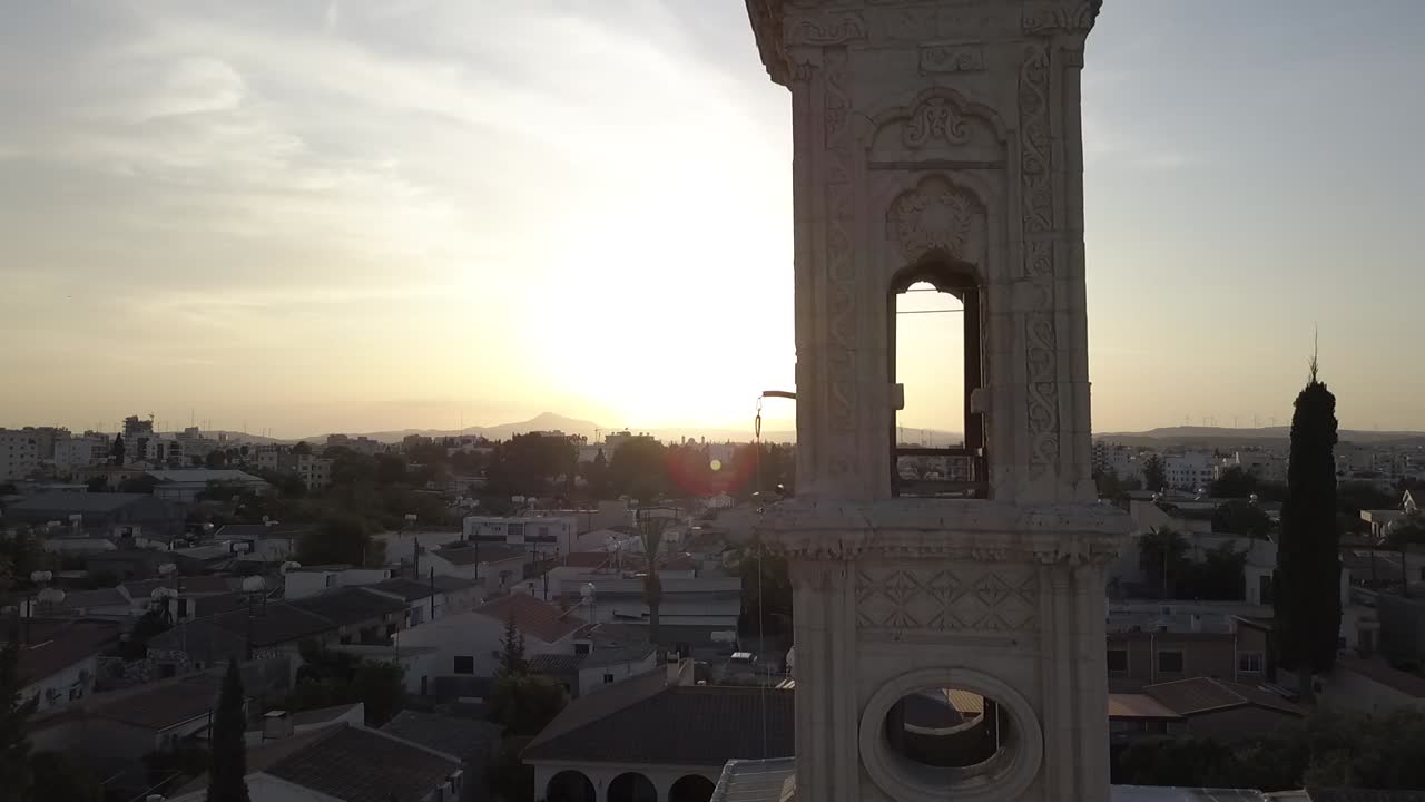 toma aérea rodeando la torre de una iglesia con campanas sonando al atardecer