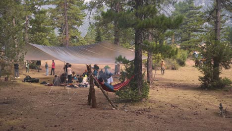 slowmotion panning shot of a woodland camp being setup with a man sleeping in a hammock