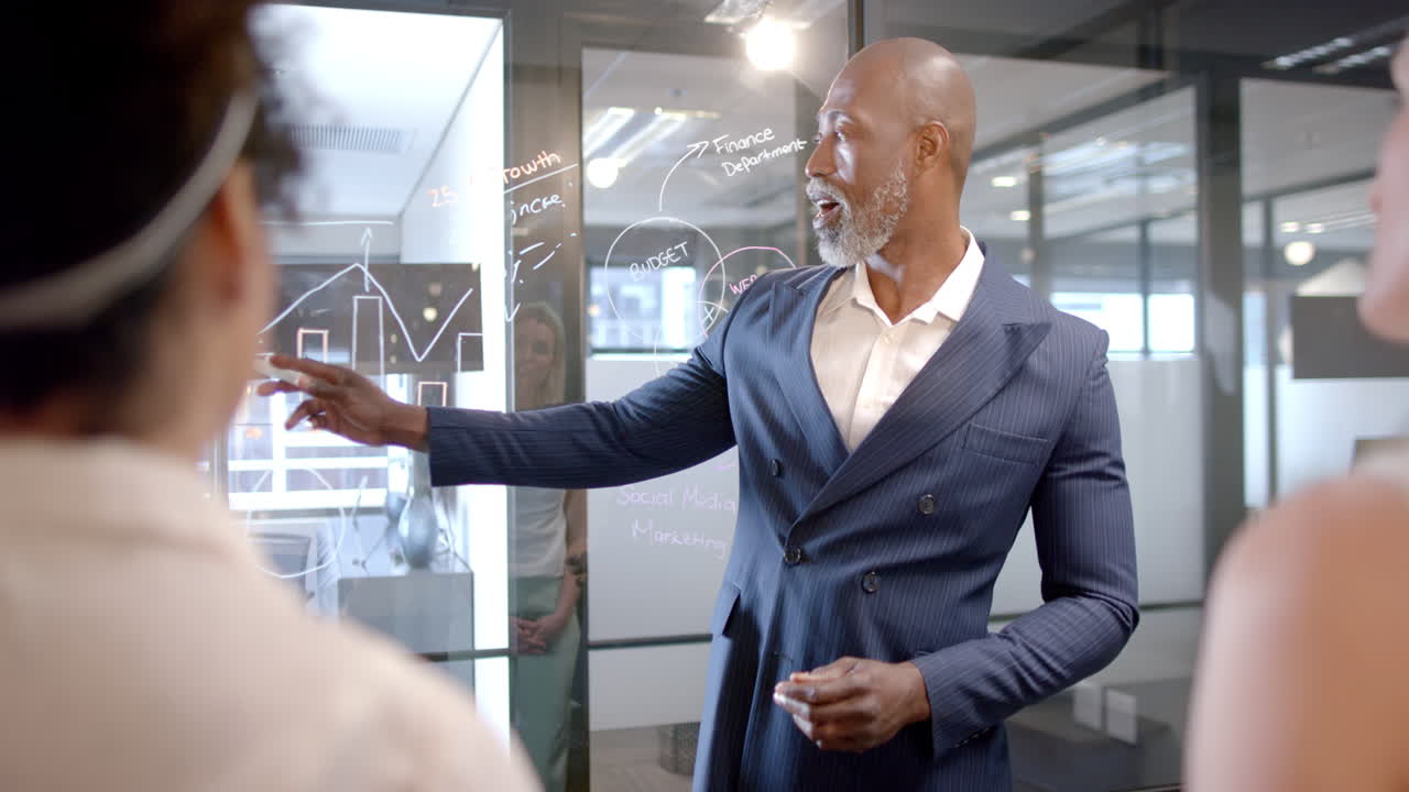 African american businessman writing on glass wall in office with copy space