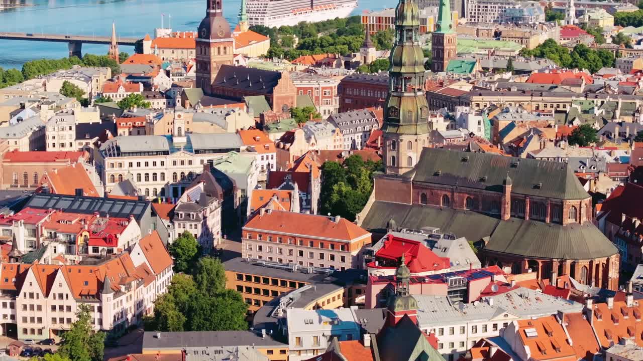 Church spires and red rooftops dominate Riga Old Town in bright aerial view