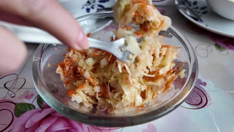 an elderly woman mixes a salad with carrots, onions and apples for dinner