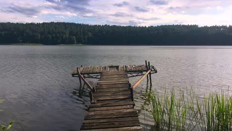 Vista-De-Cerca-De-Las-Ondas-De-Agua-Creando-Un-Efecto-Dominó,-Vista-De-Un-Muelle-De-Madera-En-Un-Lago-Con-Fondo-Natural