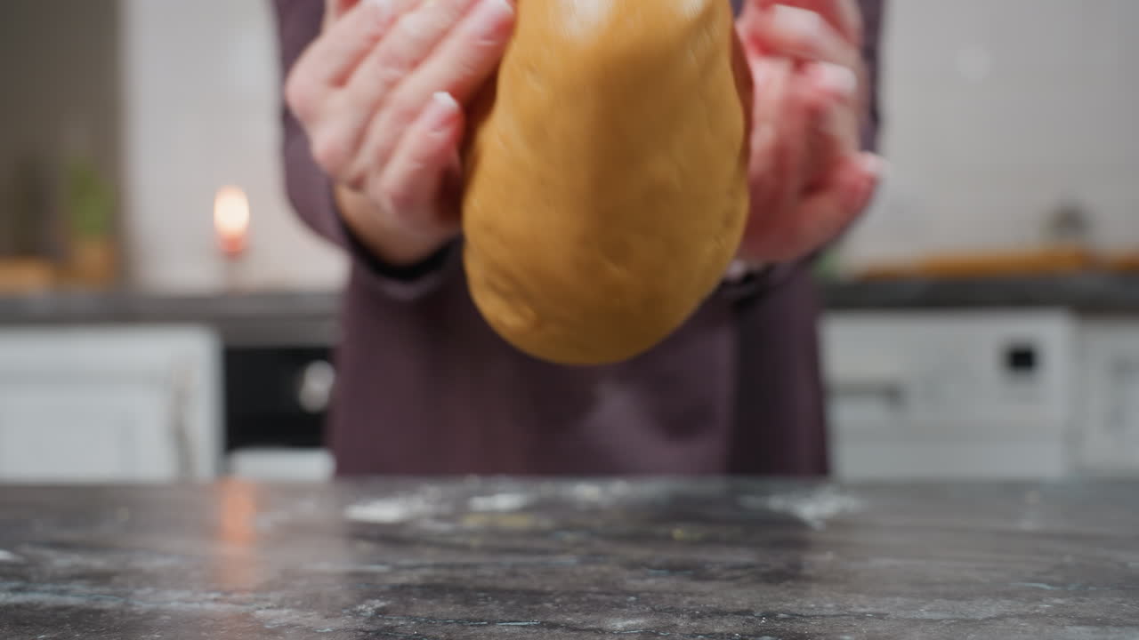 베이커가 반죽을 고, 그것을 들어 올리고, 부 테이블에 떨어뜨리는 모습, 손이 움직이고, 반죽이 공중에 서서히, 밀가루 먼지가 표면에, 현대 부 설정 배경