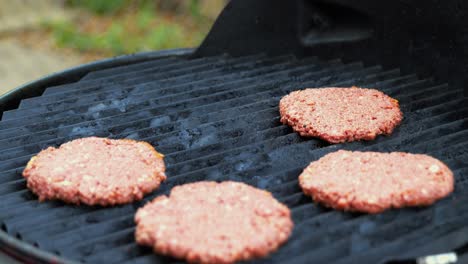 placing seasoned raw plant based impossible meat burger patties on electric grill with metal spatula at outdoor barbecue at home - in cinema 4k