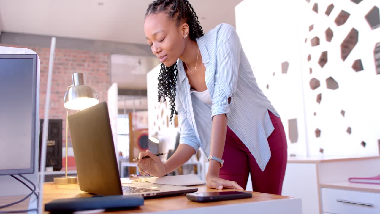 mulher de negócios afro-americana feliz usando laptop no escritório, câmera lenta