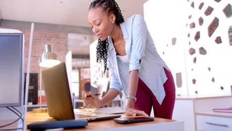 happy african american casual businesswoman using laptop in office, slow motion