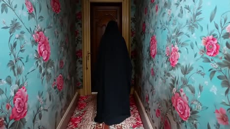 a woman in a blue robe walking down a hallway with roses on the walls