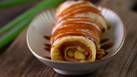 Pouring-thick-soy-sauce-over-Taiwanese-omelette,-egg-pancake-roll.