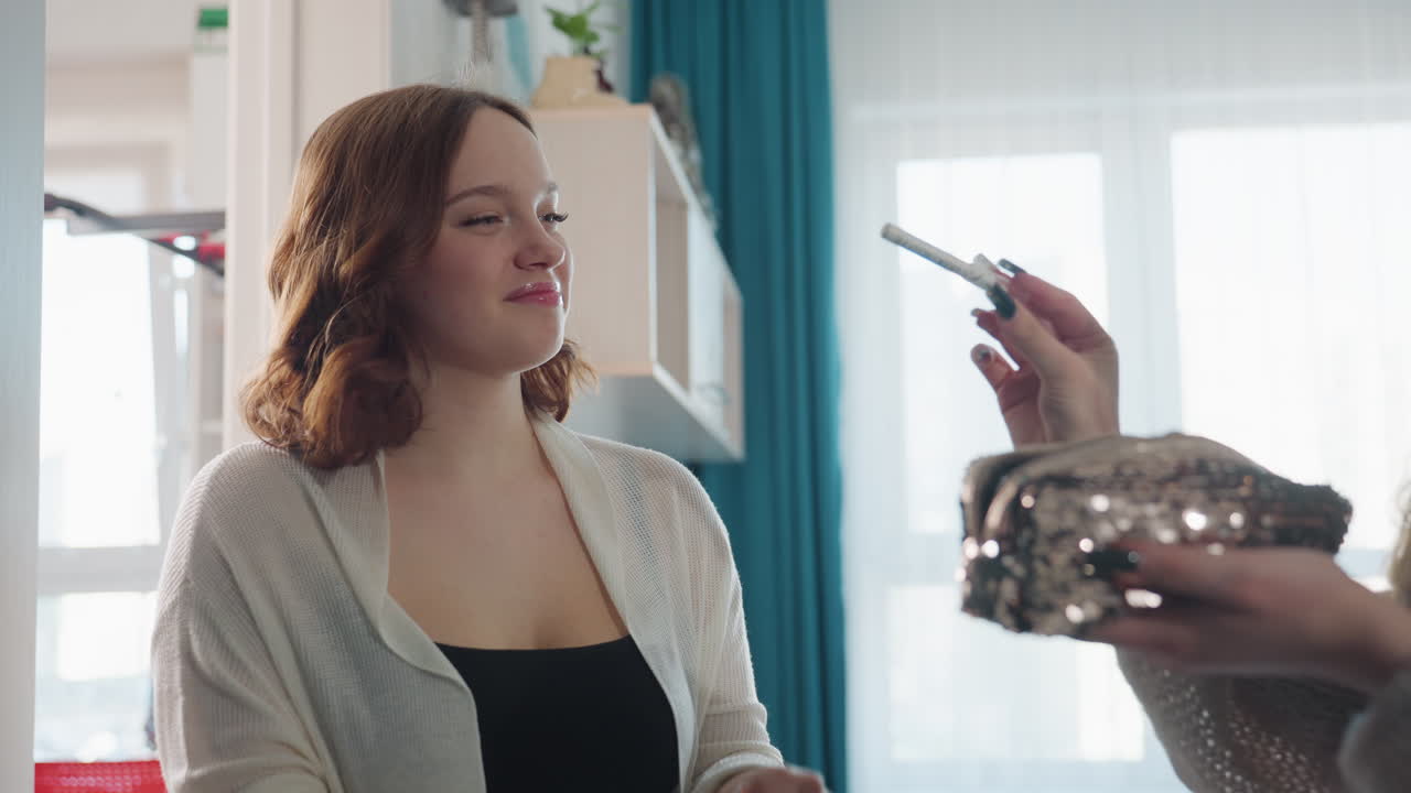Casual Interaction Involving Woman Testing Lipstick By Window With Cheerful Expression, Spontaneous Moment Capturing Woman Examining Lipstick Color Next To Sunlight With Joyful Reaction