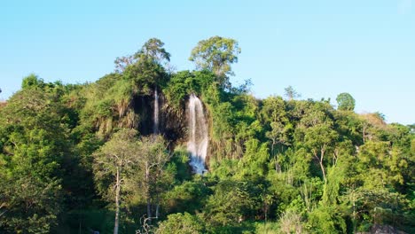 A-wide-view-of-the-natural-waterfall-that-flows-down-the-mountain-is-lit-by-the-evening-sun-in-Thailand