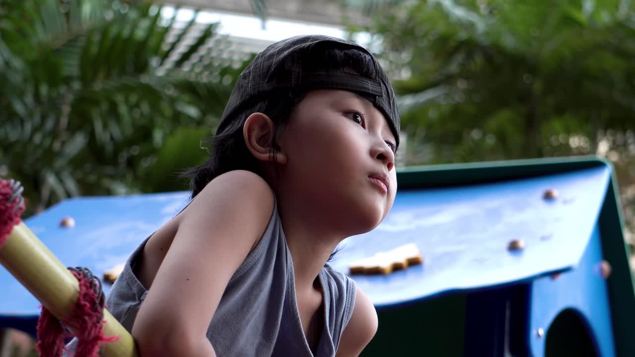 toma artística de un puente de cuerda deshilachado en el patio de recreo con niños jugando fuera de foco en el fondo