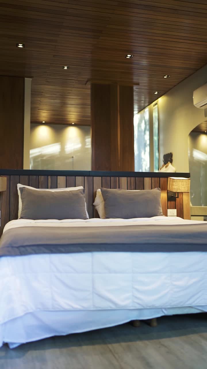 Modern hotel room featuring wooden ceiling, headboard, and column, creating a warm and inviting atmosphere for guests seeking relaxation and comfort, establishing shot