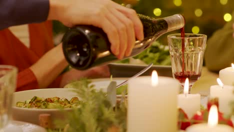 close up shot of the man pouring the red wine in the glass during the winter holiday celebration