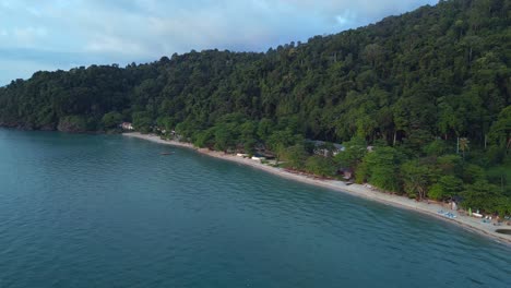 long narrow sandy beach behind jungle and mountains