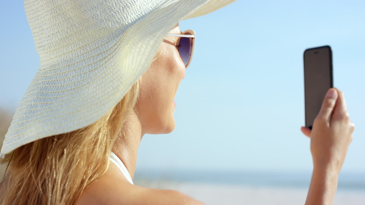 해변에 앉아 전화 통신을 사용하여 가까운 여성 비디오 메시징