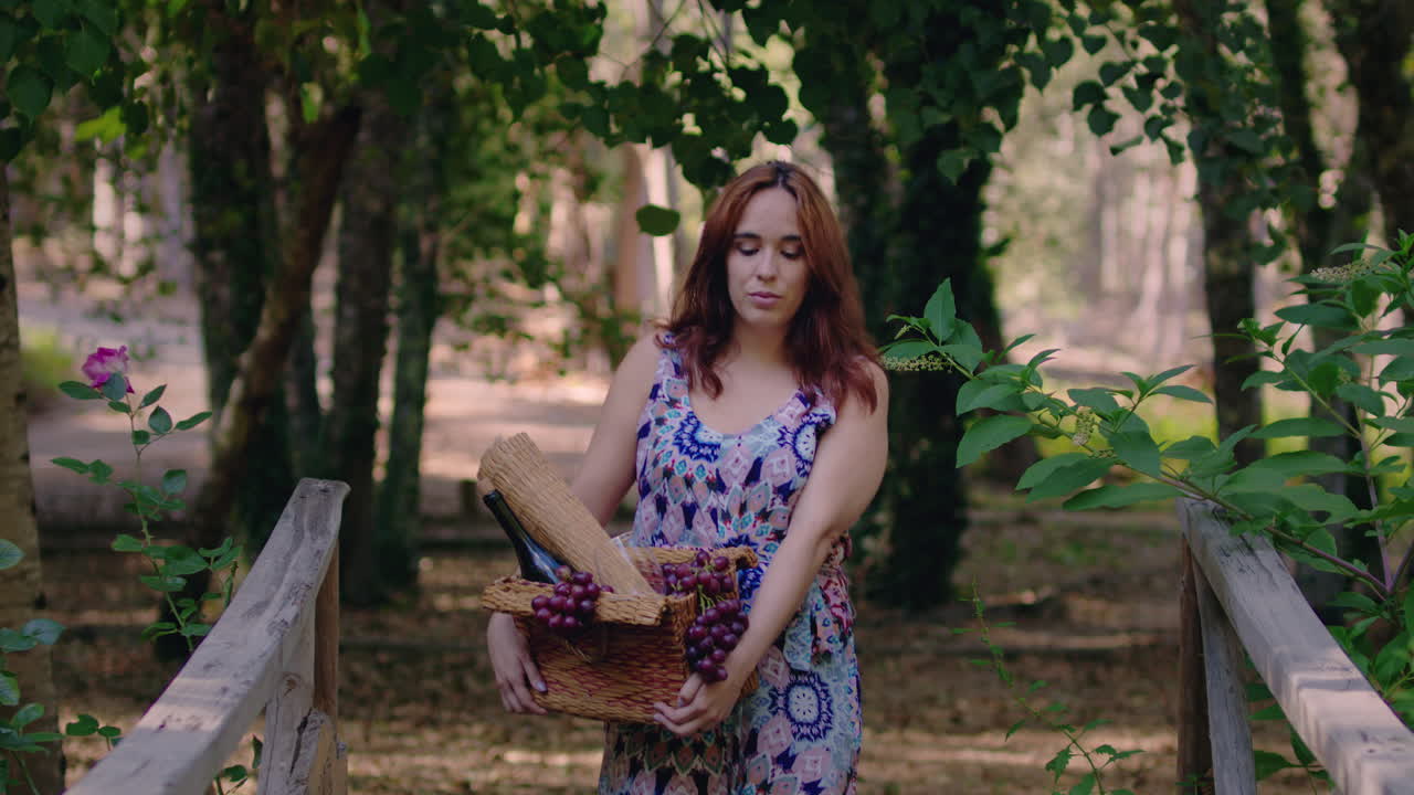 chica camina en un parque con una canasta de vino y uvas medio tiro