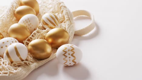 Bag-with-white-and-gold-easter-eggs-on-white-background-with-copy-space