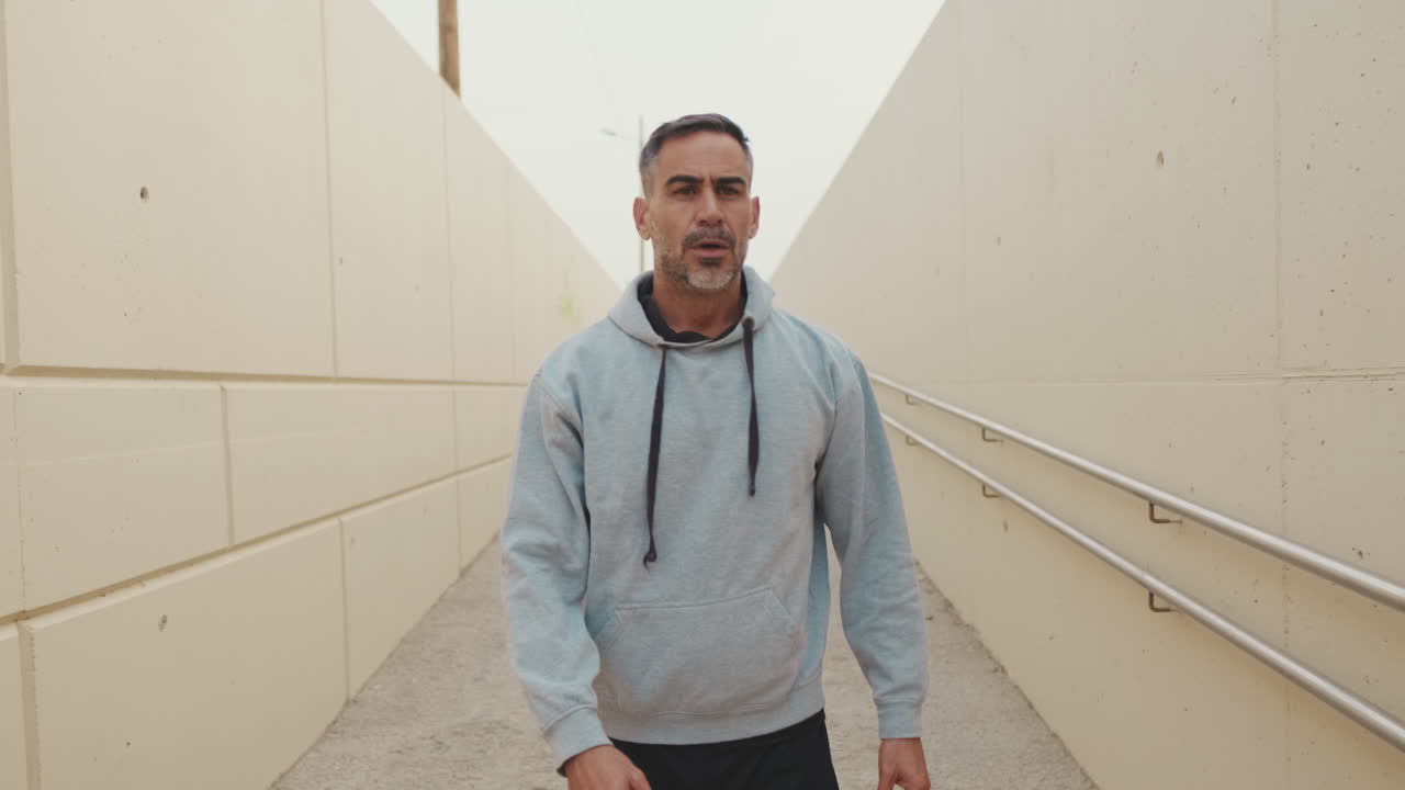 Uomo con felpa con cappuccio che cammina in un tunnel
