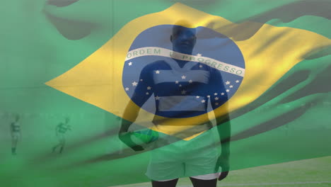 animation of brazilian flag waving, african american male player with rugby ball standing on ground