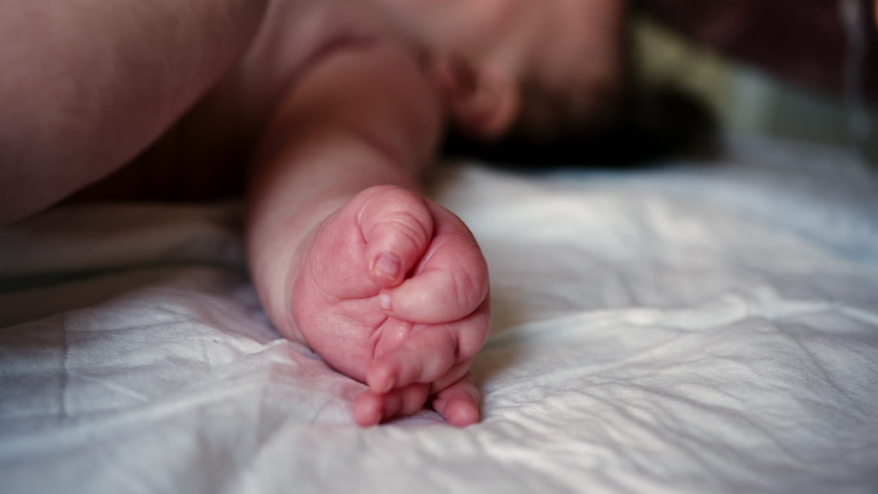 Omsorgsperson, der laver mobilitetsøvelser med en baby.