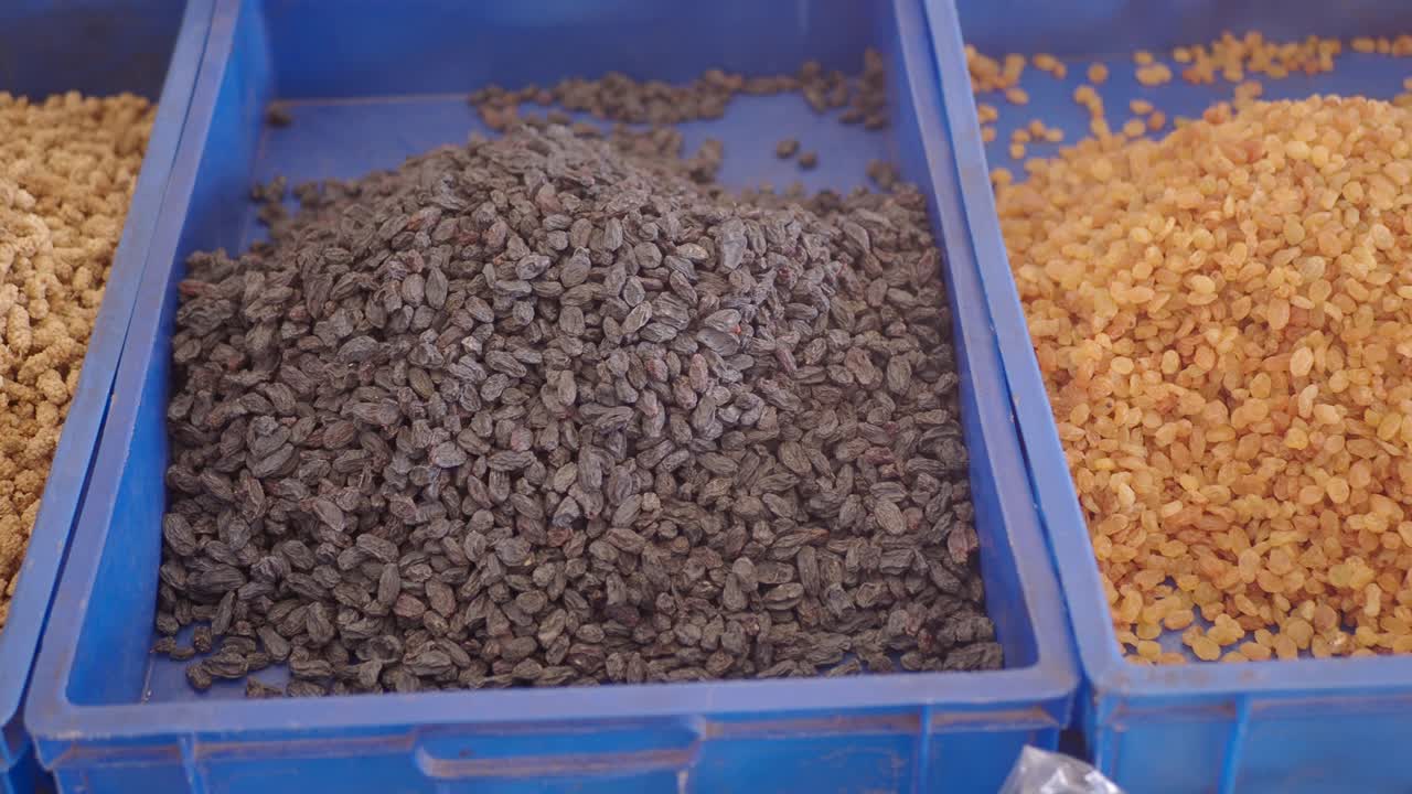 Different colored raisins in plastic bins at a market