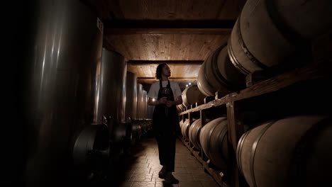 authentic shot of successful male sommelier is tasting a flavor and checking white wine quality poured in transparent glass in a wine cellar.