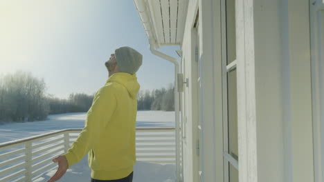 Young-happy-man-enjoys-first-spring-sun-outside-his-forest-home,-side-view