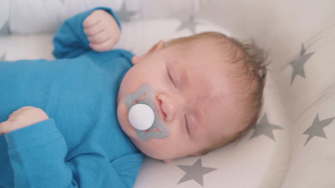 little child sucks dummy falling asleep on rocking crib