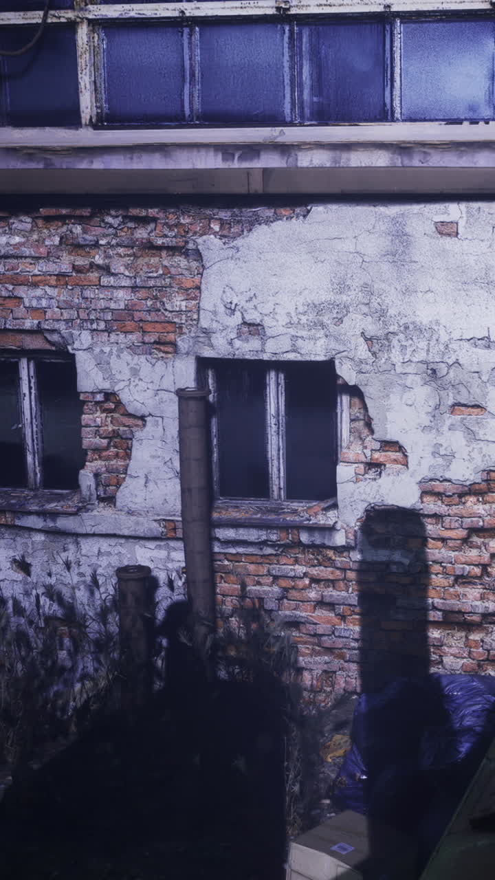 Vecchio edificio in mattoni con finestre rotte in un'area scarsamente illuminata.