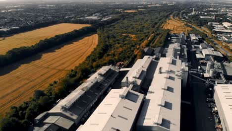 aerial view of industrial complex overlooking lush fields and verdant landscape: a contrast between urban development and natural surroundings