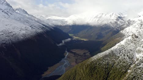 increíble valle con montañas nevadas arriba con un río corriendo en un día nublado en nueva zelanda