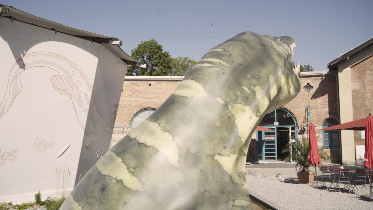 Smooth close up gimbal shot of the dinosaur exhibition
focussing on the entrance of the museum, in Rosenheim
city with its interesting architecture and a dinosaur figure.